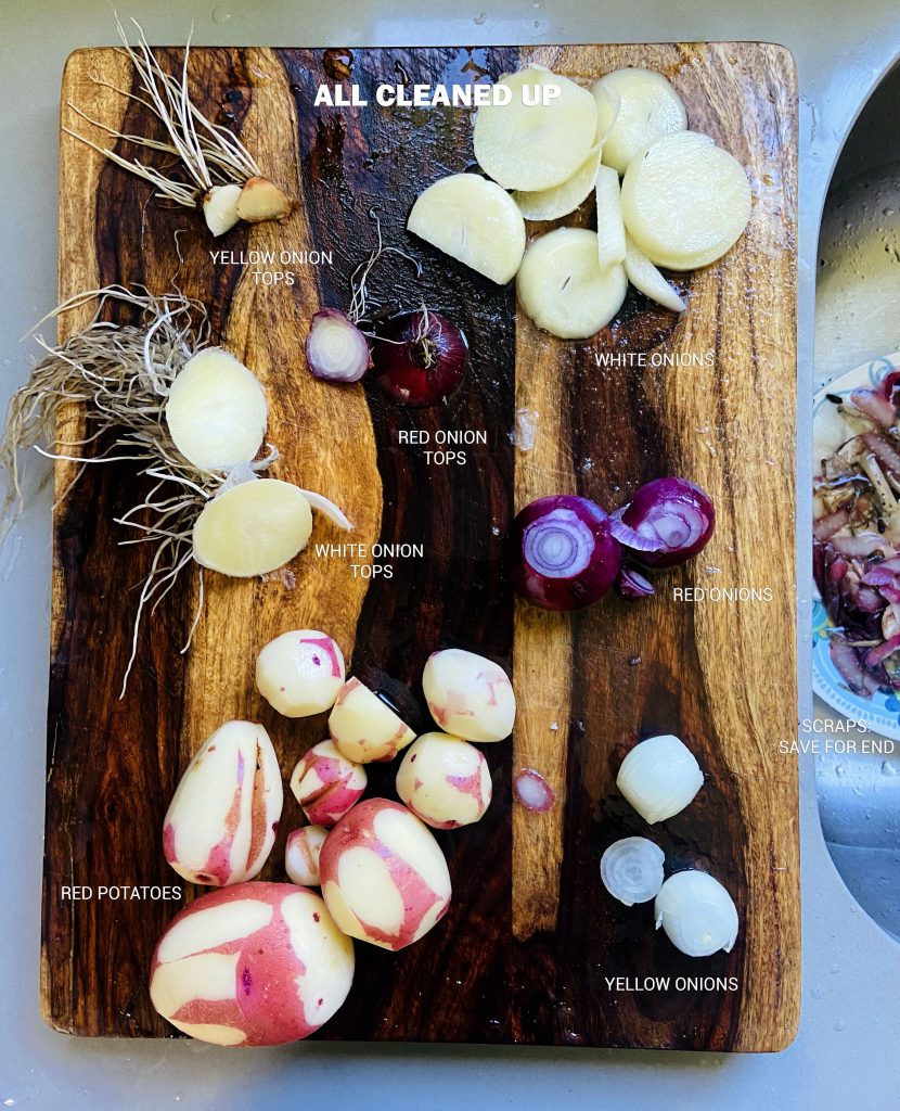 Freshly rinsed red potatoes, yellow, white and red onions. The tops of the onions are cut off. 